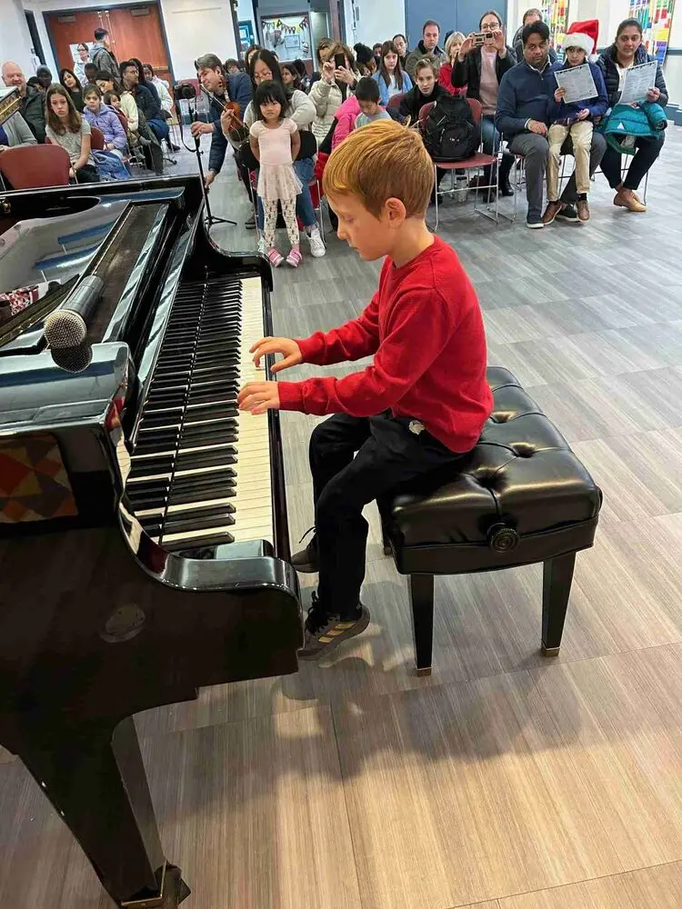 A young Allegro Music School student enchants the audience with his piano performance at the Winter Recital.