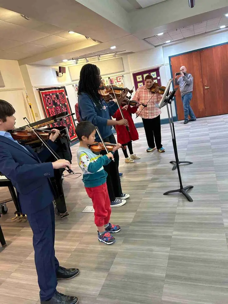 A group of violinists performs together at the Allegro Music School Winter Recital 2024, showcasing teamwork.